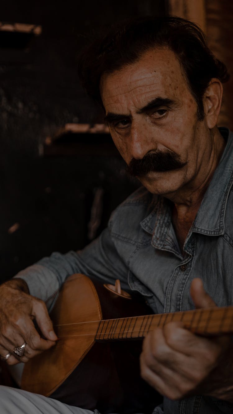 A Mature Man Playing A Brown Stringed Instrument