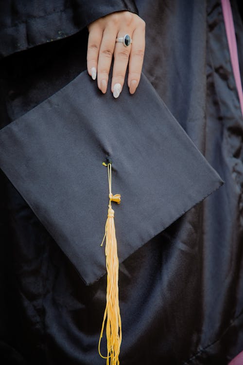 Close-Up Shot of a Person Holding a Black Graduation Cap · Free Stock Photo