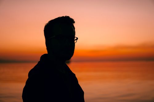 Free A man silhouetted against a vibrant sunset over the water in Istanbul, Turkey. Stock Photo