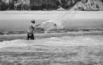 在巴西拜亚福尔摩沙，一张黑白照片记录了一名渔民撒网的瞬间