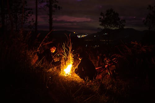 People Sitting by Bonfire at Night