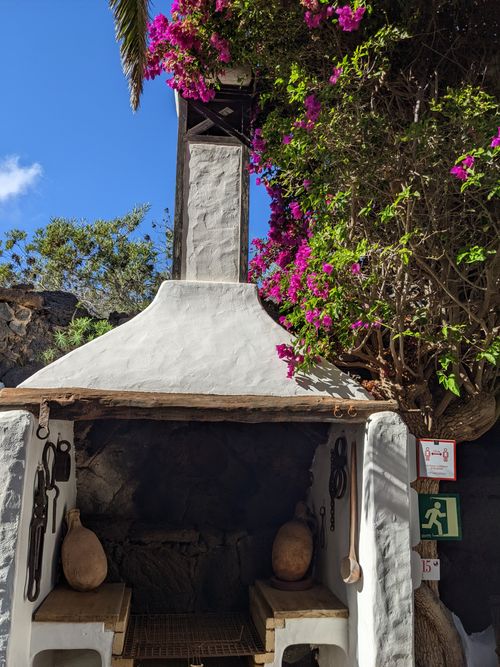 Free Rustic white outdoor fireplace adorned with vibrant bougainvillea in sunny Teguise, Spain. Stock Photo