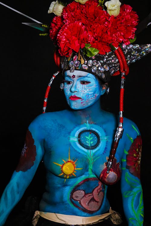 A woman with blue body paint and flowers on her head