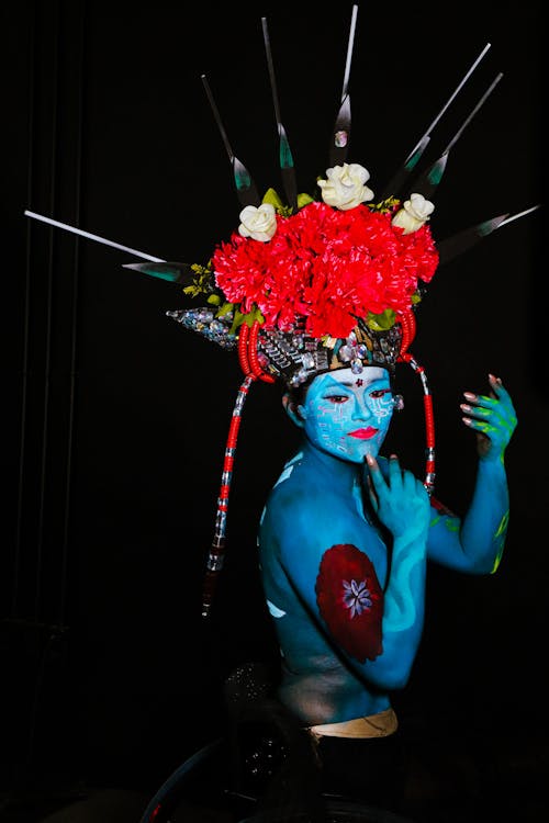 A man with blue face paint and flowers on his head