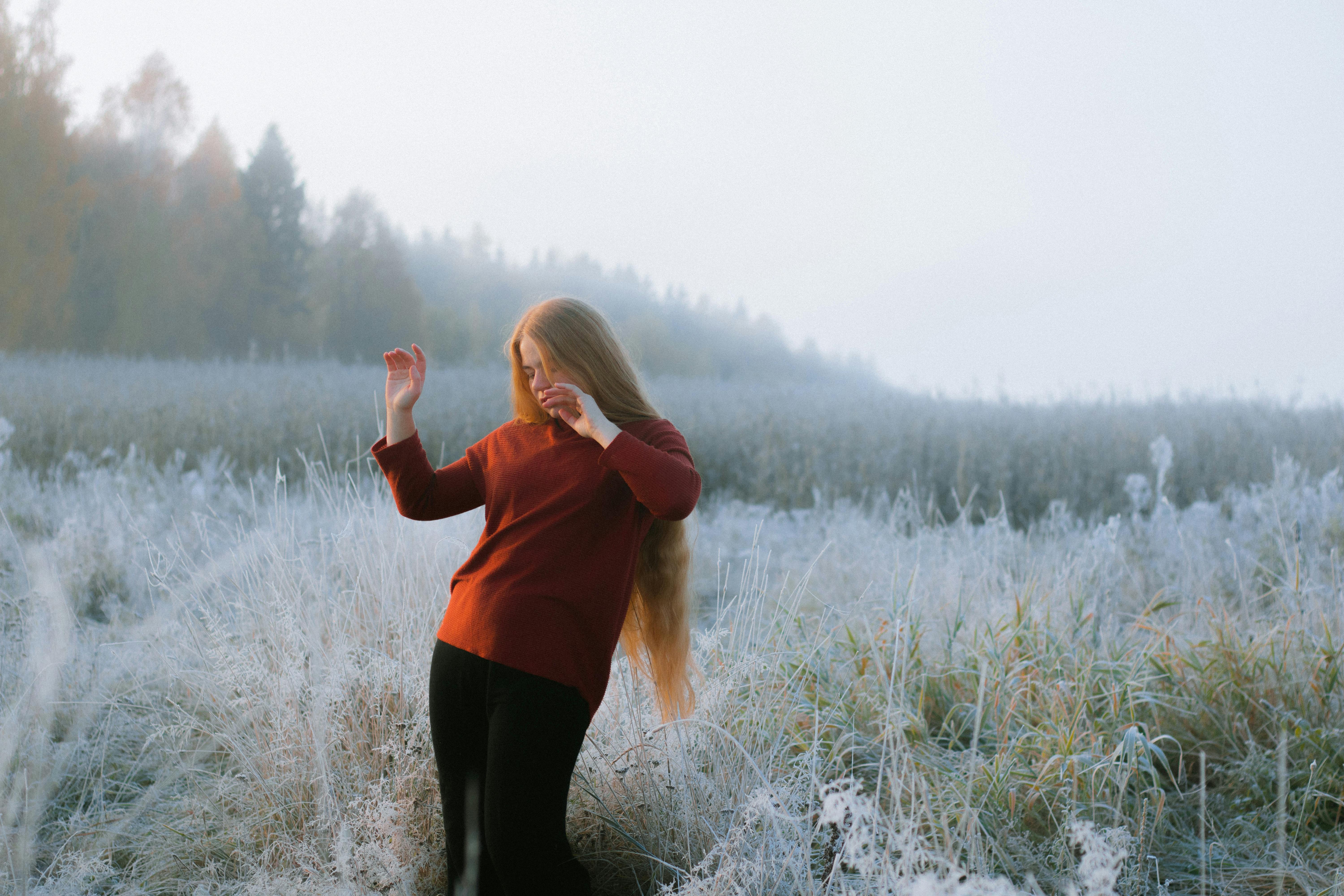 photo of a posing woman with long hair standing on a winter meadow