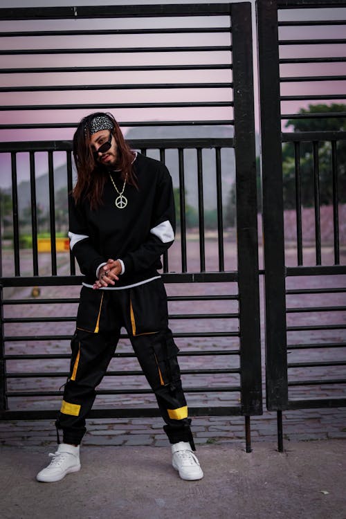 A man in Black Clothing Standing in Front of a Metal Gate