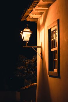 A vintage lamp illuminates a colonial building exterior at night in Tiradentes, Brazil.