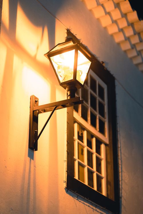 Free Charming colonial-style lamp casting warm light on a window in Tiradentes at night. Stock Photo