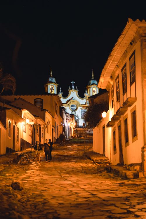 Free Beautiful illuminated colonial street in Tiradentes, Brazil at night with church in the background. Stock Photo