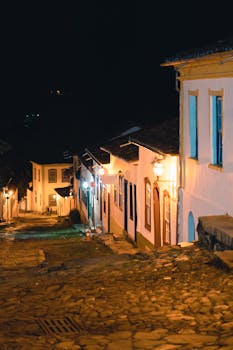 Cobblestone street of Tiradentes, MG, Brazil at night with illuminated colonial buildings.