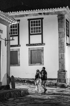 A couple walks on cobblestone streets in historic Tiradentes, Brazil, at night.