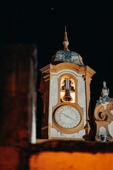 Illuminated baroque church tower against the night sky in Tiradentes, Brazil.