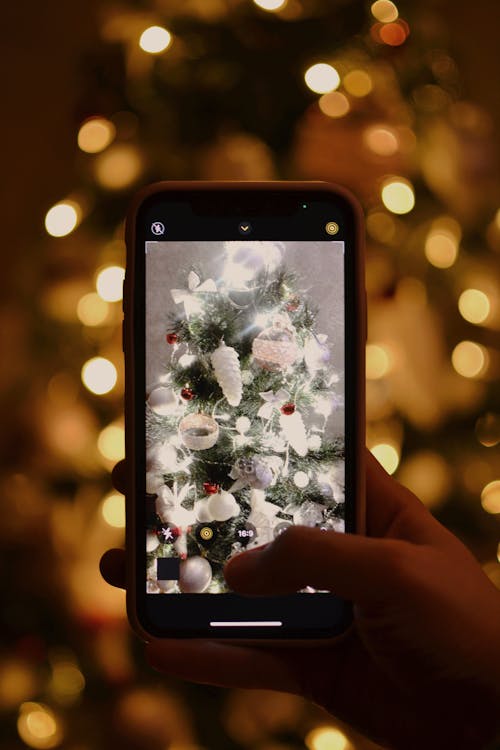 A Hand Taking Photos of the Beautiful White Christmas Tree