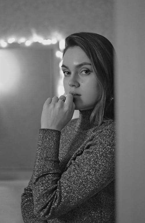 Grayscale Photo of Woman in Turtleneck Sweater With Hand on Her Mouth 