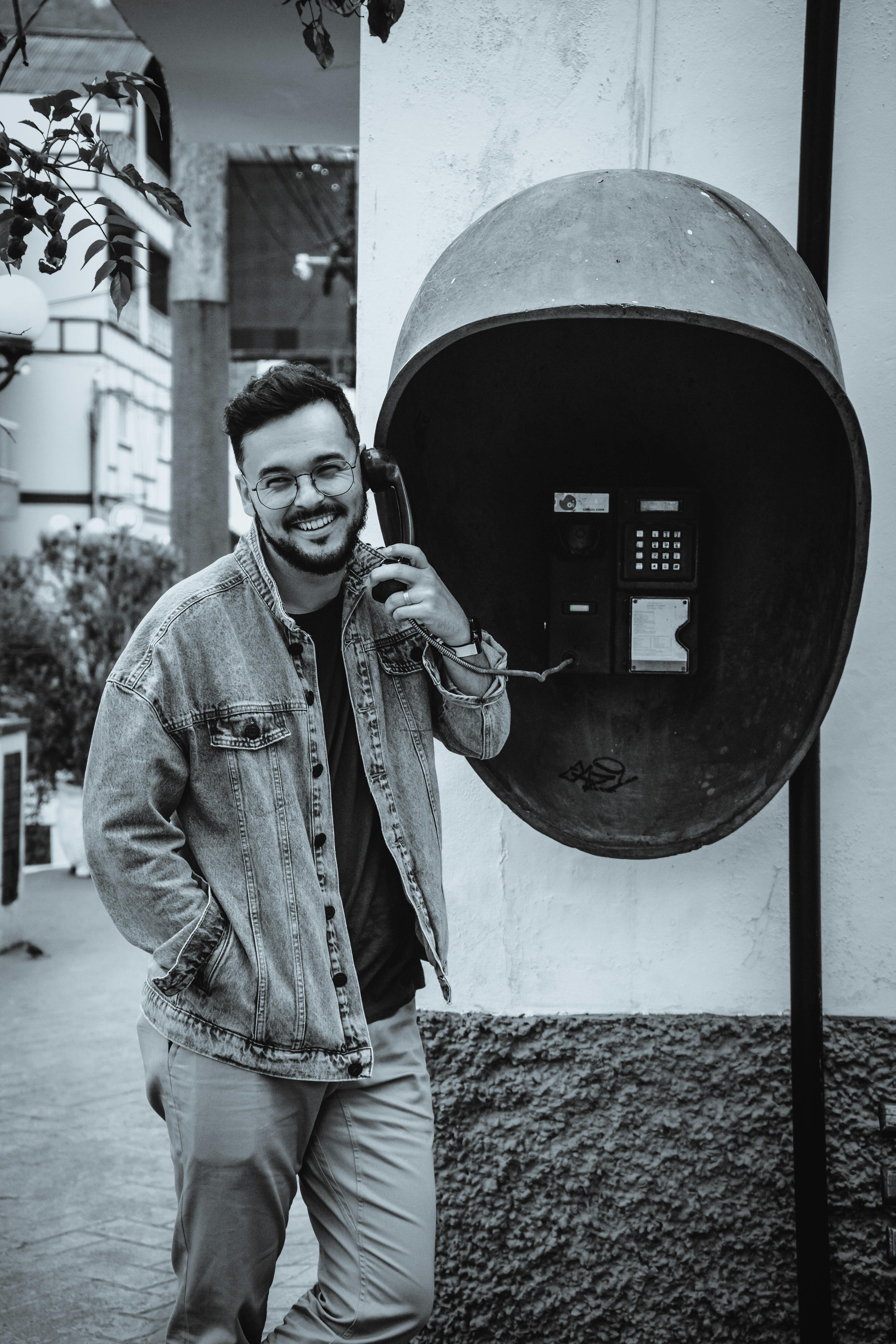 A cheerful man using a vintage public phone, adding a nostalgic urban touch.