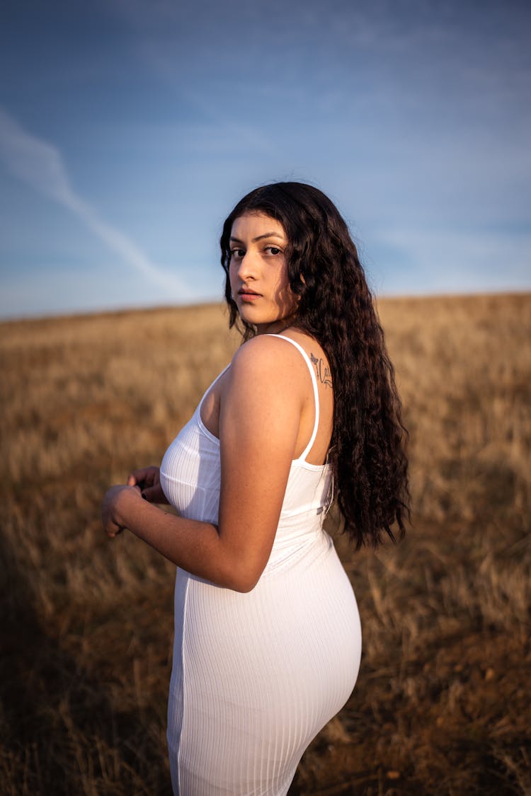 Woman With Curly Hair Looking Over Her Shoulder In A Field