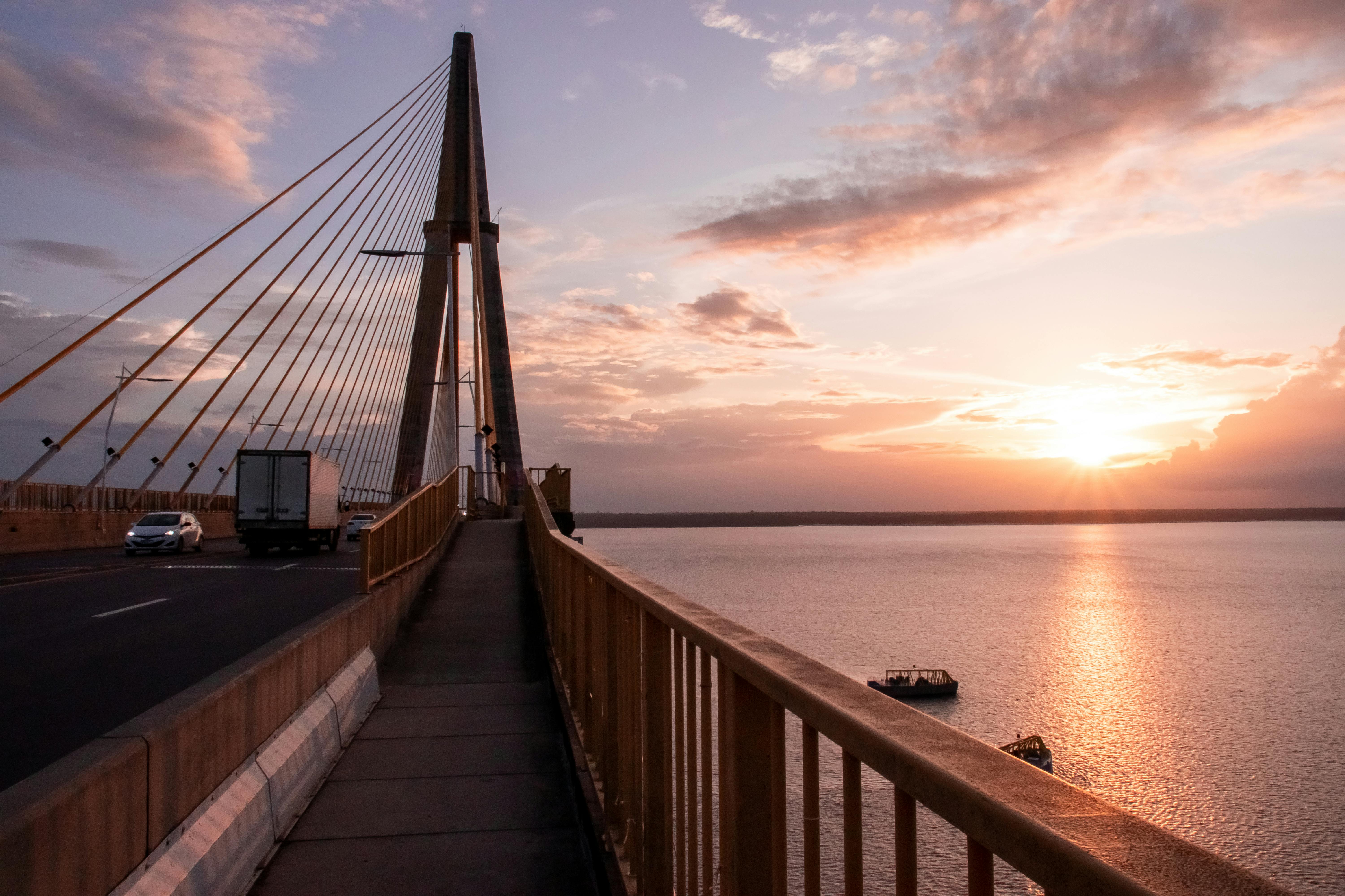 a bridge over water with a sunset in the background