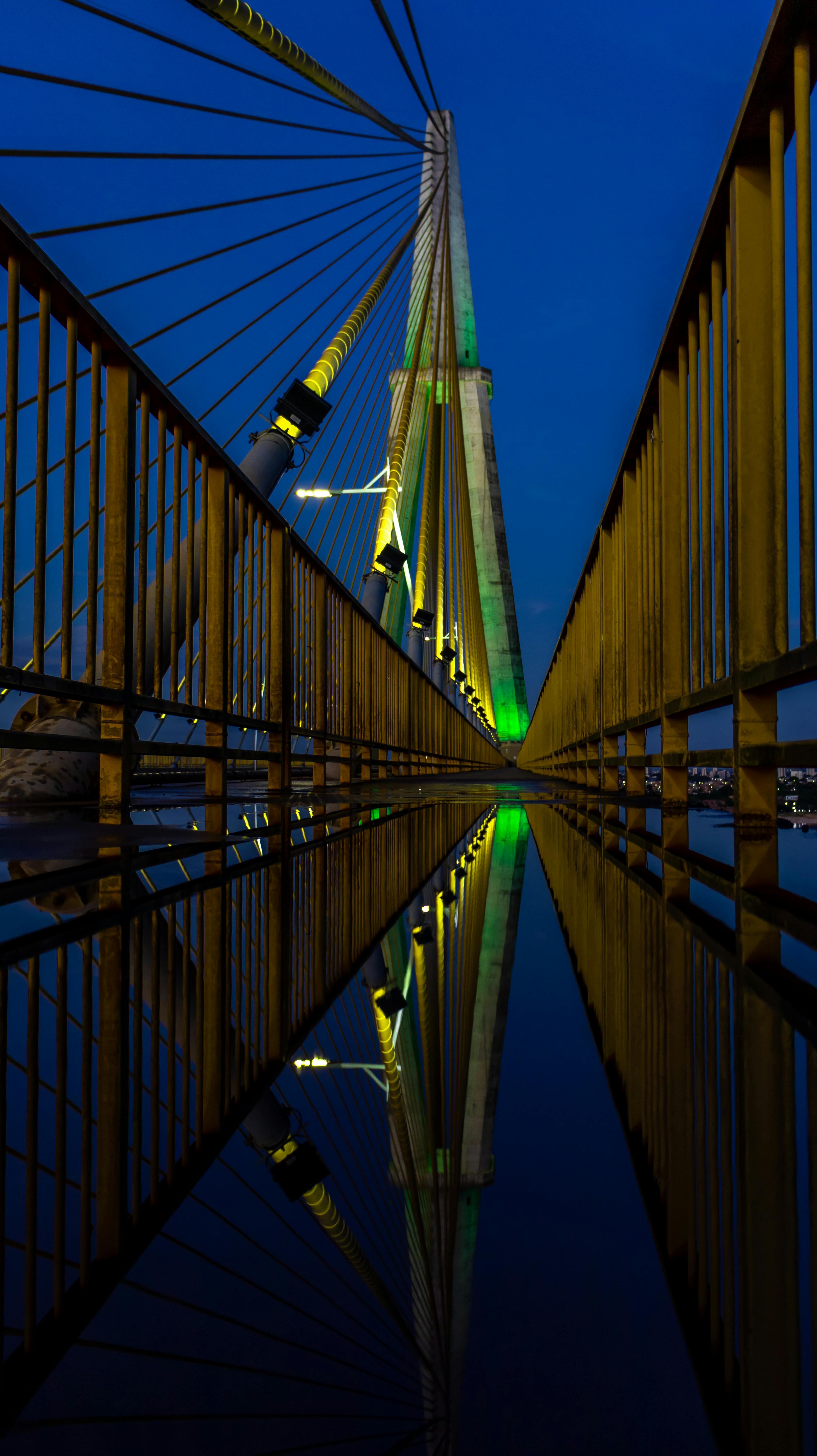 a bridge with green and blue lights reflecting in the water