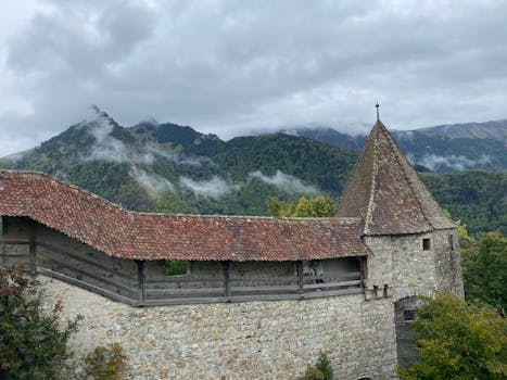 Scenic view of medieval stone architecture in Gruyères, surrounded by misty mountains.