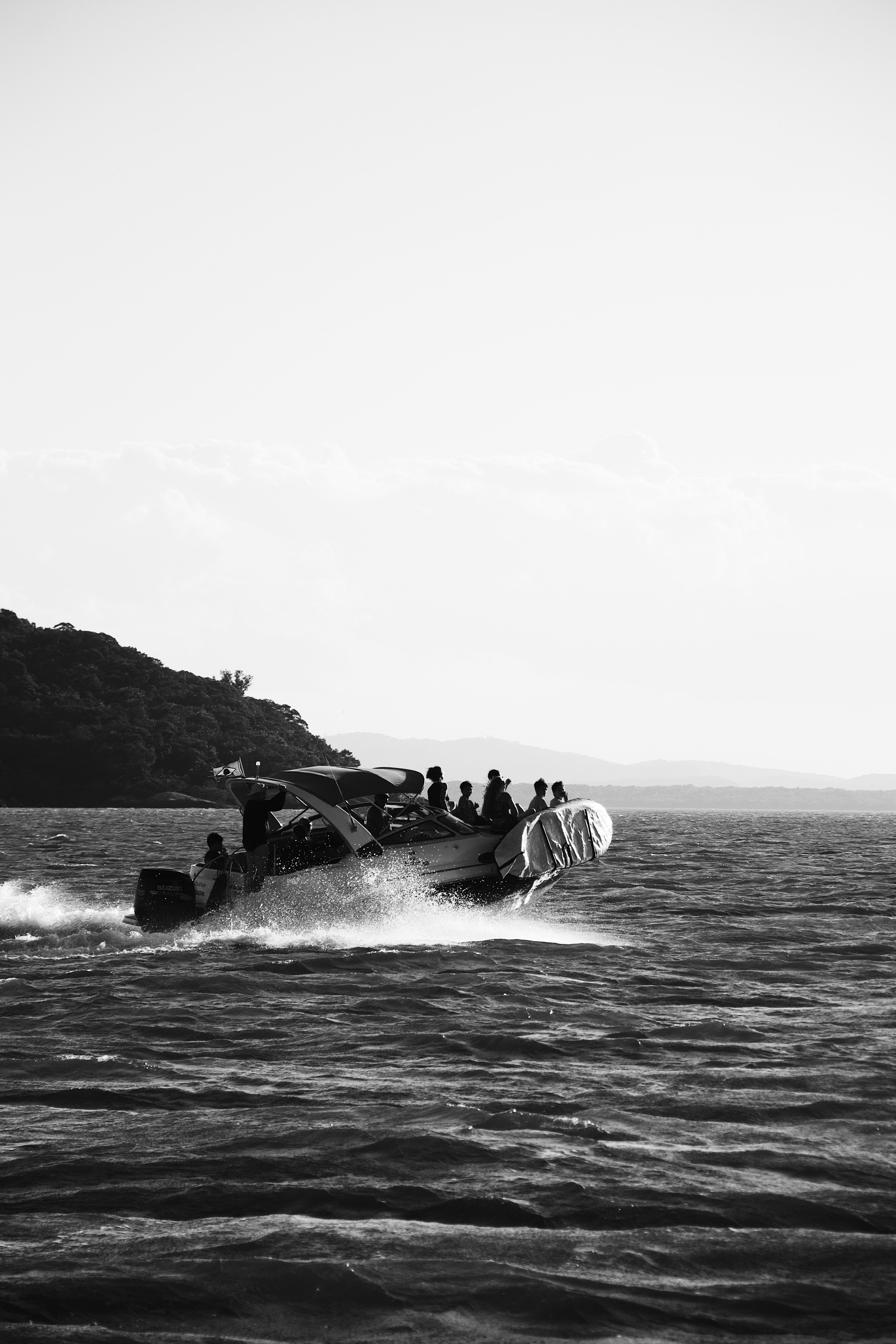 A black and white image of a boat with people navigating the sea in Paranaguá, Brazil.