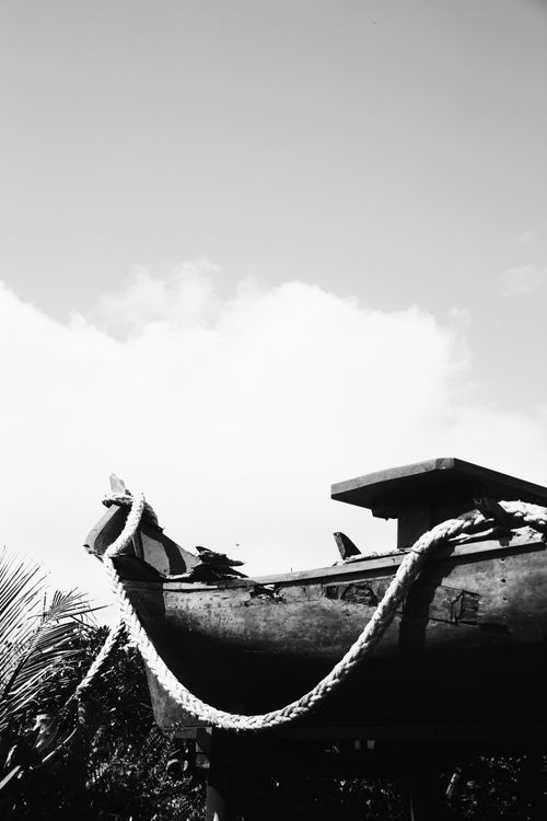Free A black and white photo of a rustic boat with rope, set against a cloudy sky in Paranaguá, Brazil. Stock Photo