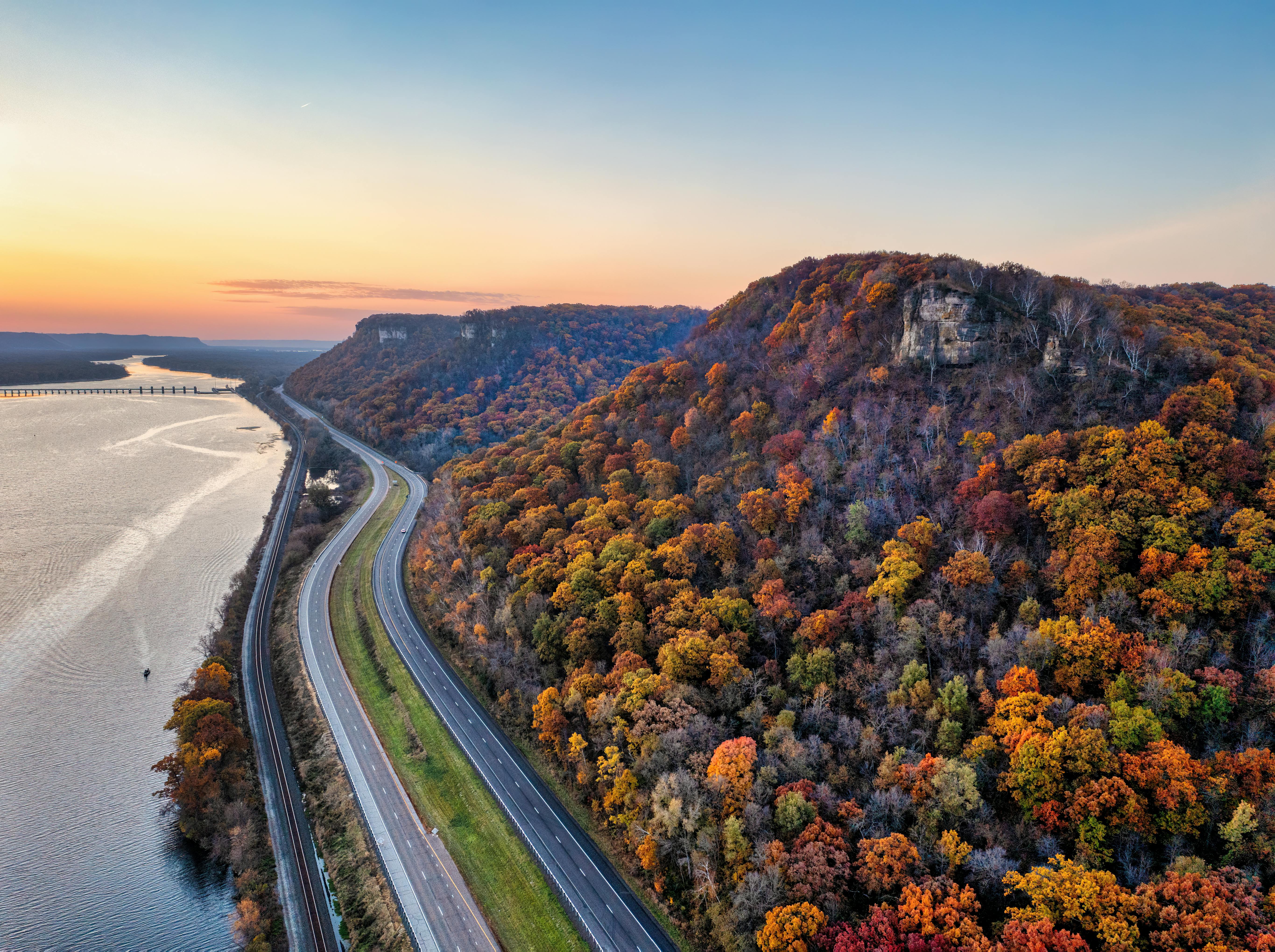 A stunning aerial view of a highway alongside a river with vibrant fall foliage in Minneiska, MN.