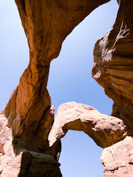 Low-angle shot of beautiful rock arches set against a clear blue sky, capturing natural grandeur.