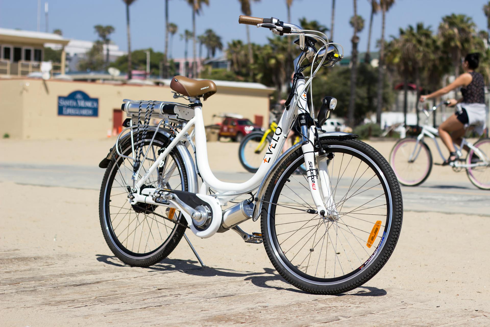 A white electric bike is parked on the beach