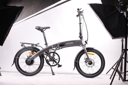 Photo by Team EVELO Modern foldable black electric bicycle displayed in a studio environment with white background and lighting equipment.