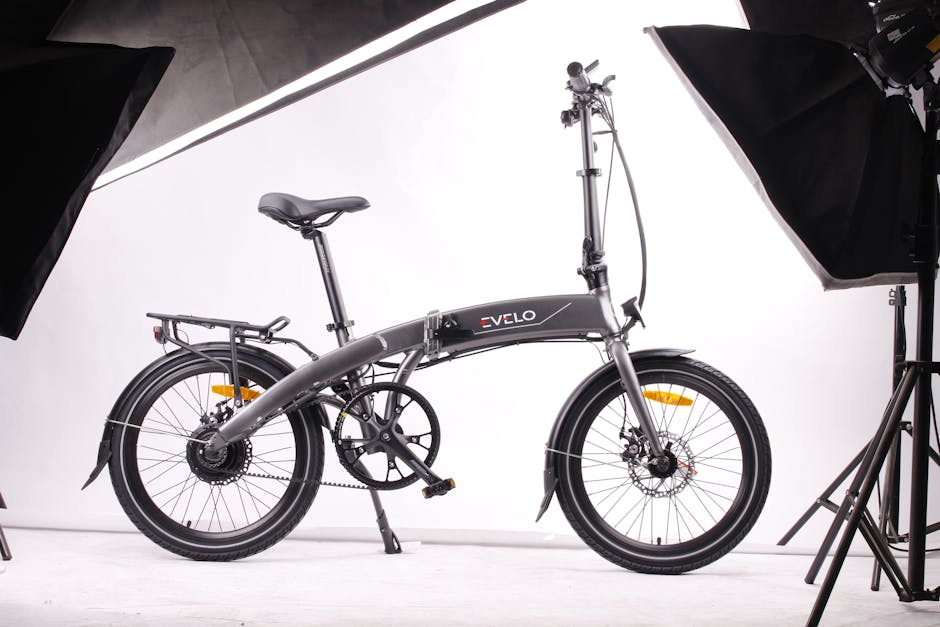 Photo by Team EVELO Modern foldable black electric bicycle displayed in a studio environment with white background and lighting equipment.