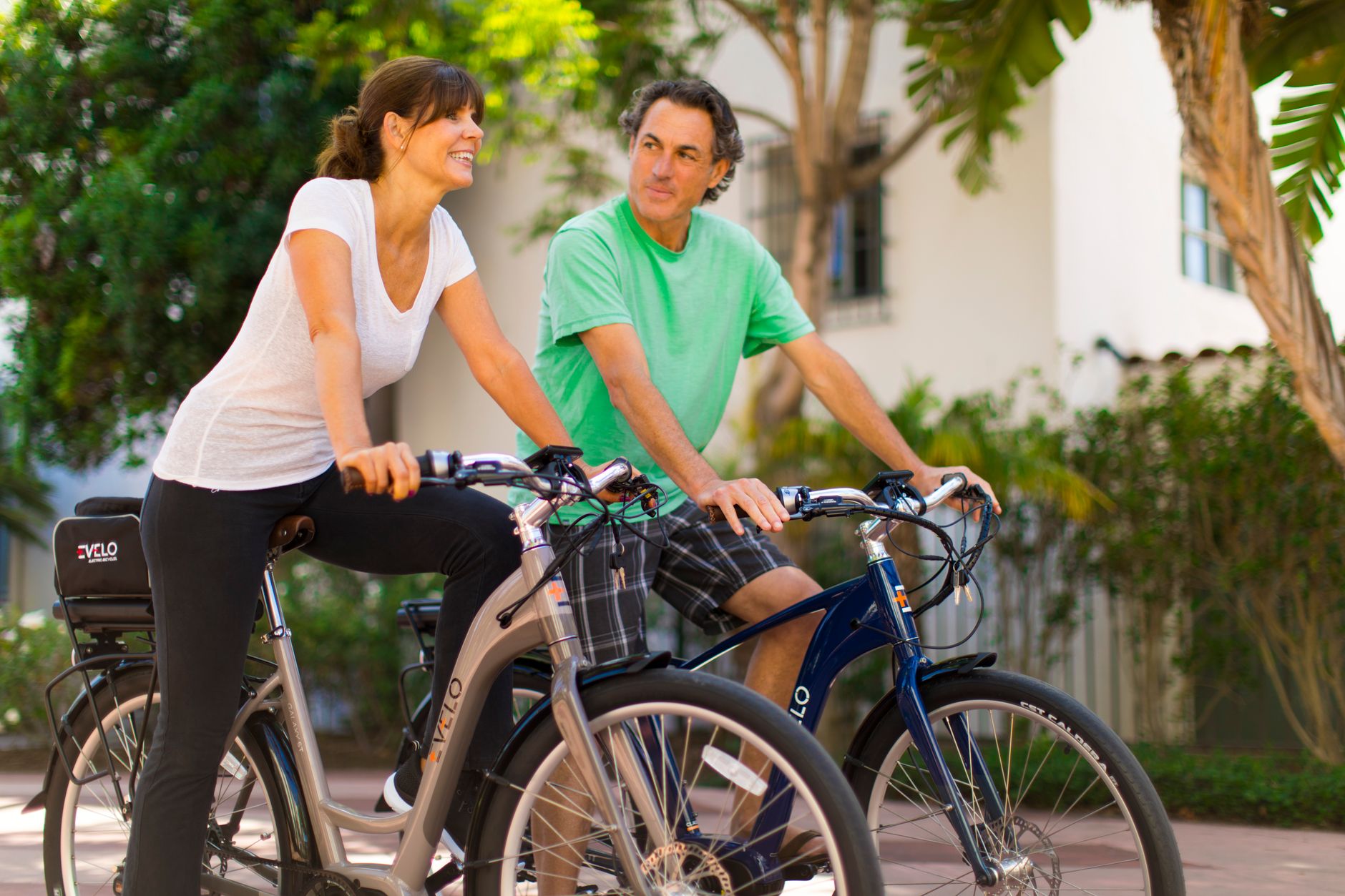 A joyful couple riding bicycles together outside on a sunny day, embracing an active and healthy lifestyle.