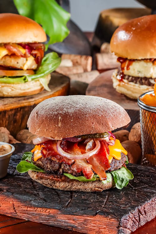 Delicious Burgers on Wooden Boards on Table