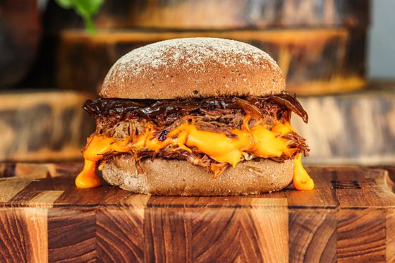 Pulled pork burger with melted cheddar sauce and caramelized onions on a floured bun