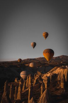 Scenic view of hot air balloons floating over Cappadocia's unique rock formations at sunrise.