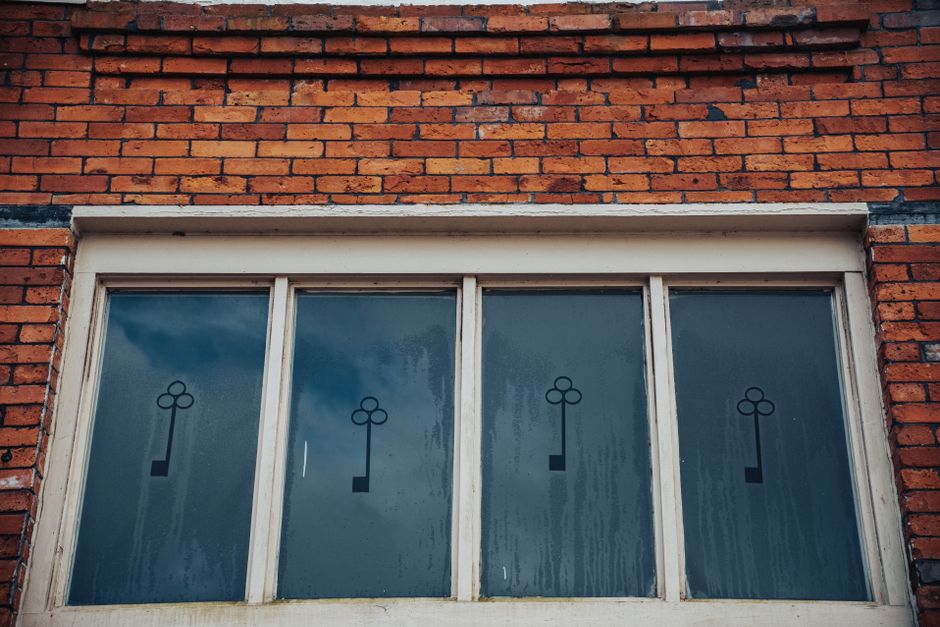 Close-up of a vintage brick wall with decorative frosted glass windows and key motif.