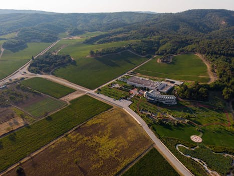 Stunning aerial view of vineyards and a luxury resort amidst rolling hills in Çanakkale, Türkiye.