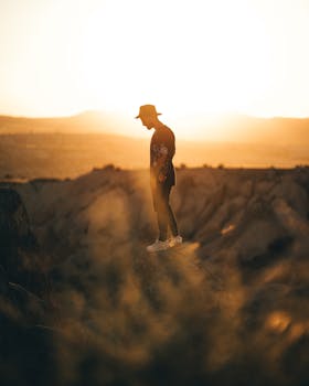 Silhouette of a man in hat standing on rock with sunrise in Ortahisar, Cappadocia, Turkey.