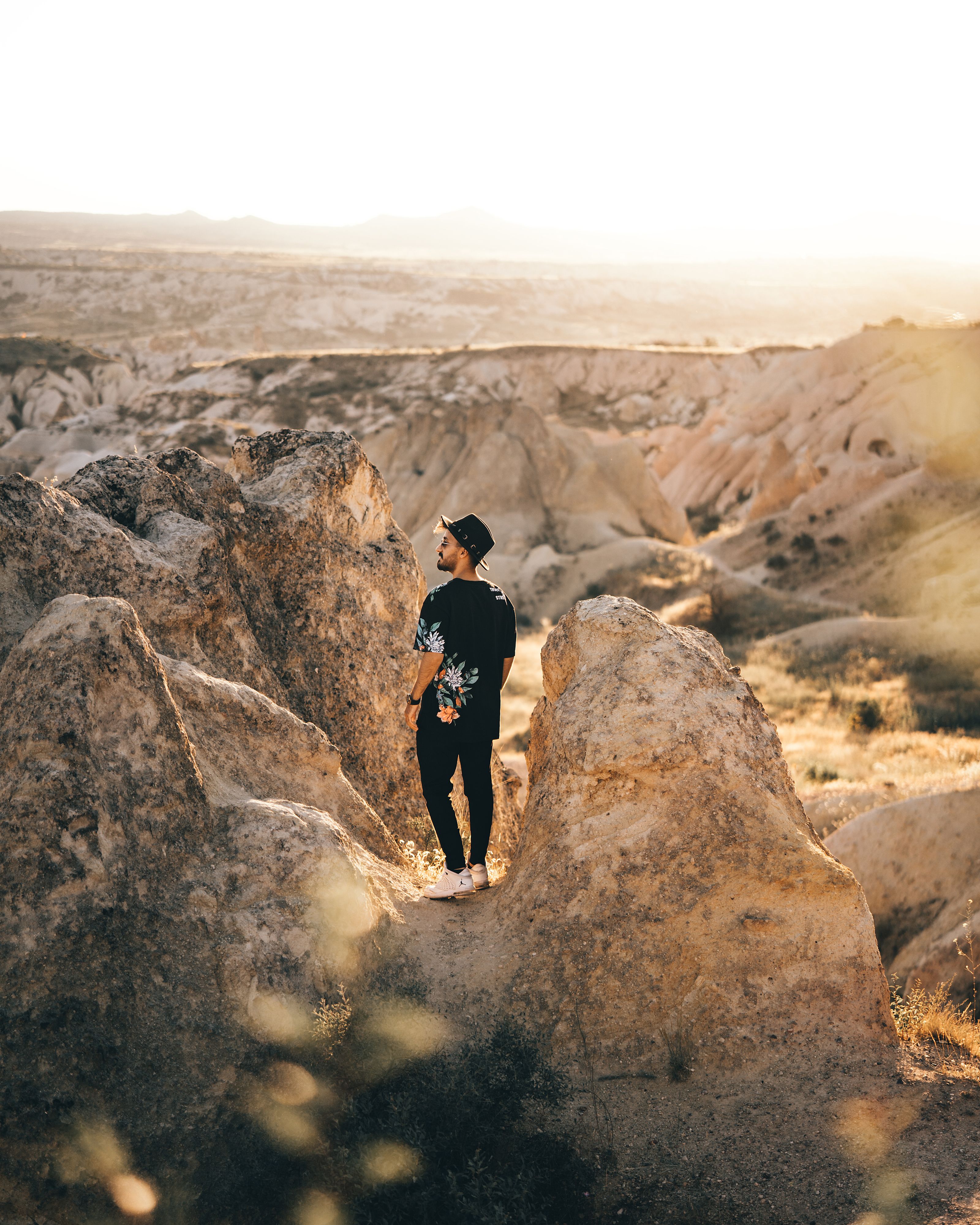 A man in stylish clothing explores Cappadocia's unique rock formations during sunrise. - Fotografer Sidoarjo