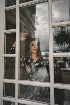 Fashionable woman standing behind a window, reflecting urban Istanbul architecture.