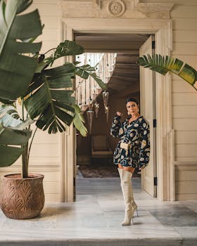 Elegant woman posing by a luxurious hotel entrance surrounded by tropical plants in Istanbul.