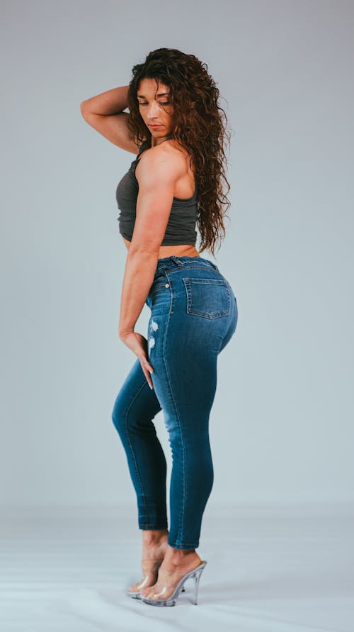 A Woman in Gray Sleeveless and Denim Jeans Posing at the Camera