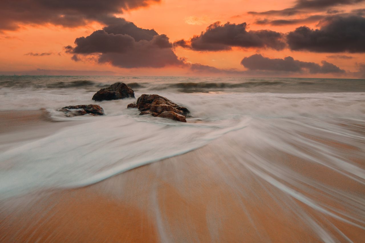 breathtaking view of the ocean waves and rocks during a warm sunset