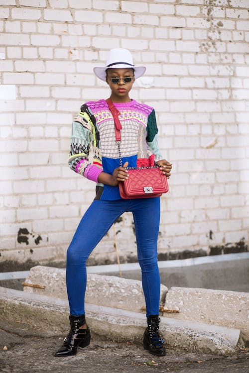 Mulher Usando Blusa Multicolorida Enquanto Segura Uma Bolsa Tipo Sling De Couro Vermelho
