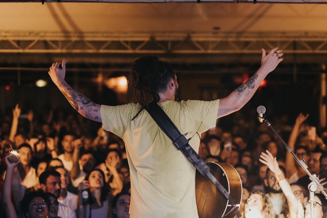 Back View of a Musician on a Stage with Arms Raised towards the Audience