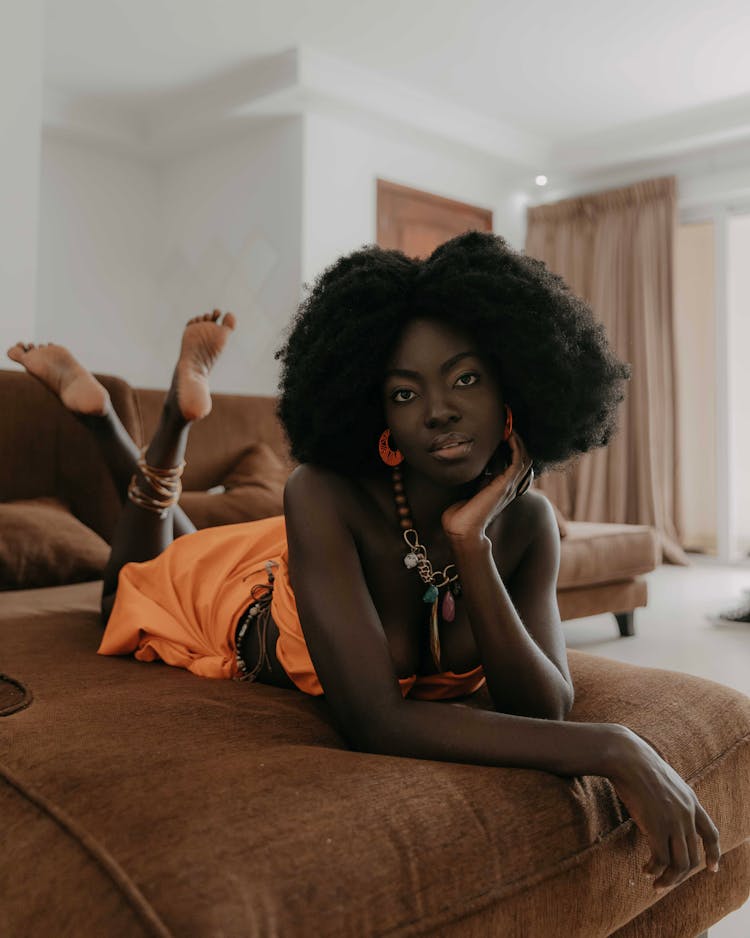 Woman In Orange Dress Lying On The Bed