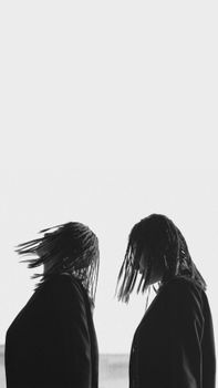 A striking black and white photo of two women in profile view with braided hairstyles.