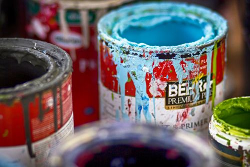 Free Close-up of vibrant, messy open paint cans with colorful splatters on a workshop surface. Stock Photo