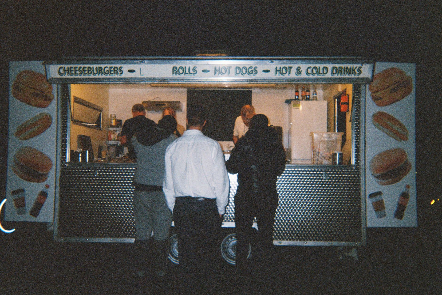 Food truck serves late-night customers ordering burgers and drinks.