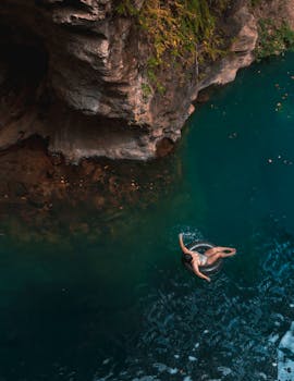Aerial view of a woman relaxing in a serene turquoise pool surrounded by rocky cliffs in Costa Rica.