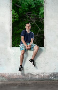 Young man sitting on a windowsill, overlooking lush greenery in Espíritu Santo, Costa Rica.